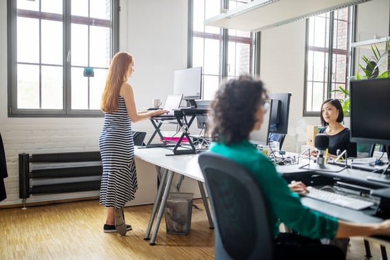 ergo keyboard tray for your office - woman standing at sit-stand desk