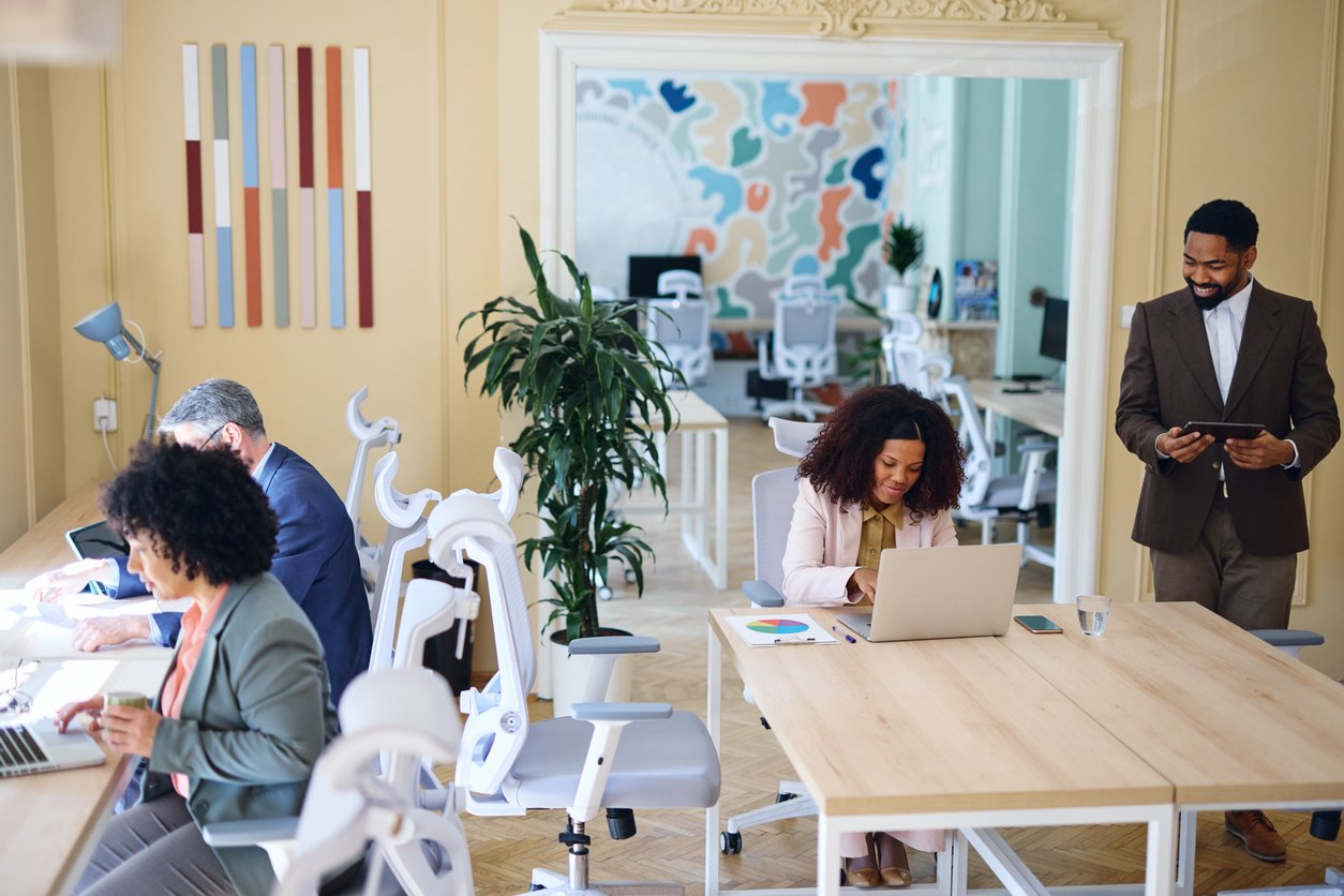 Office workers at desks and tables for an article about ergonomic furniture design and ANSI/BIFMA standards