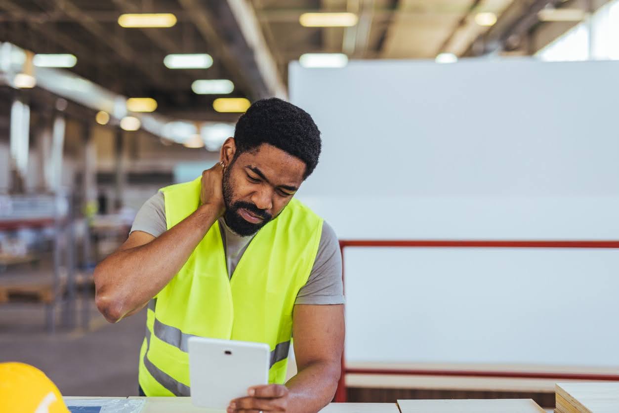 Worker experiencing neck discomfort in an industrial ergonomics setting