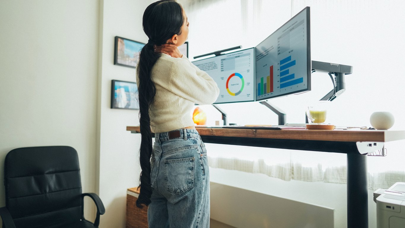 A person working at an ergonomic standing workstation with dual monitors, following ergonomic standing workstation guidelines for comfort and posture.