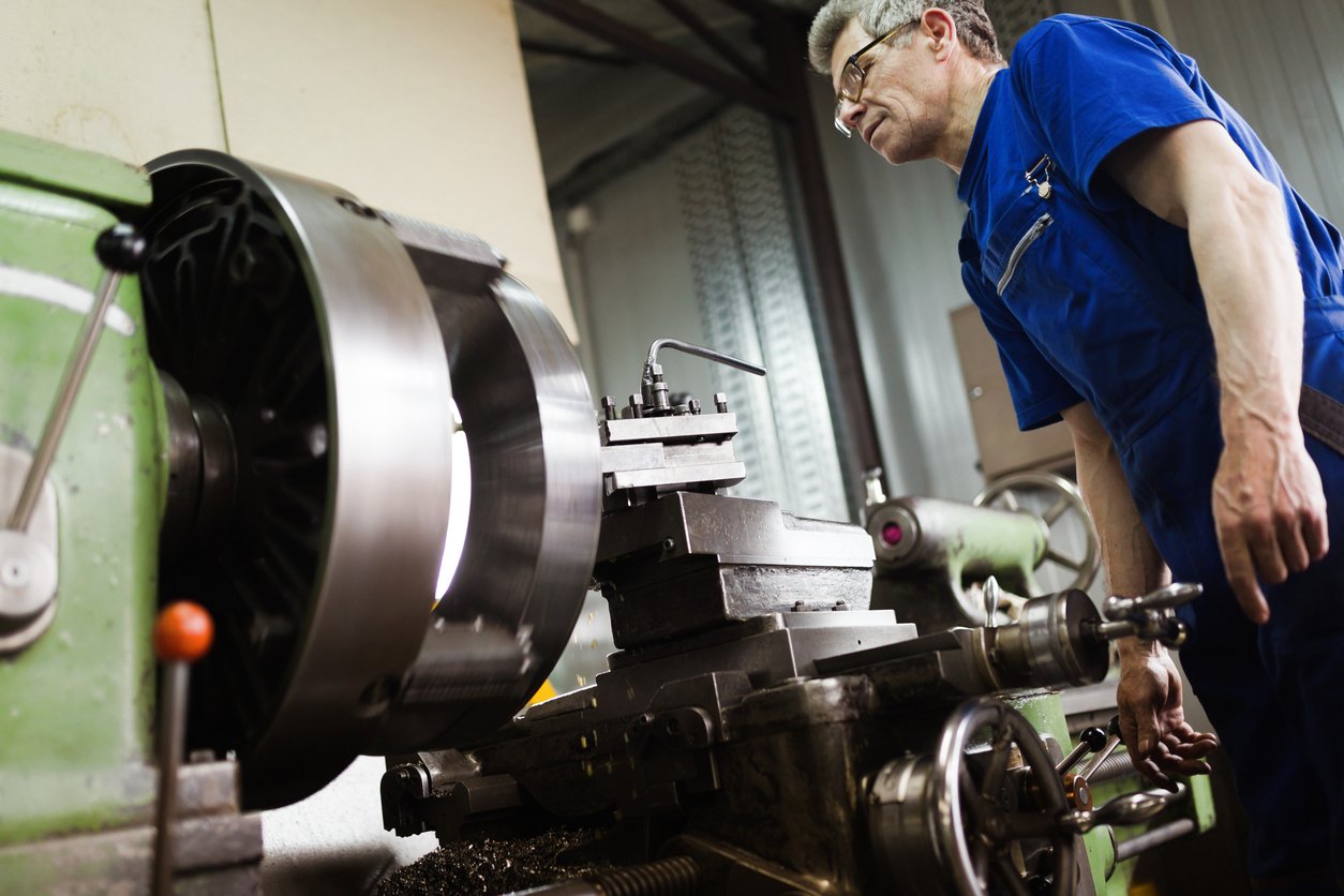 Manufacturing worker operating a metal lathe during precision machining